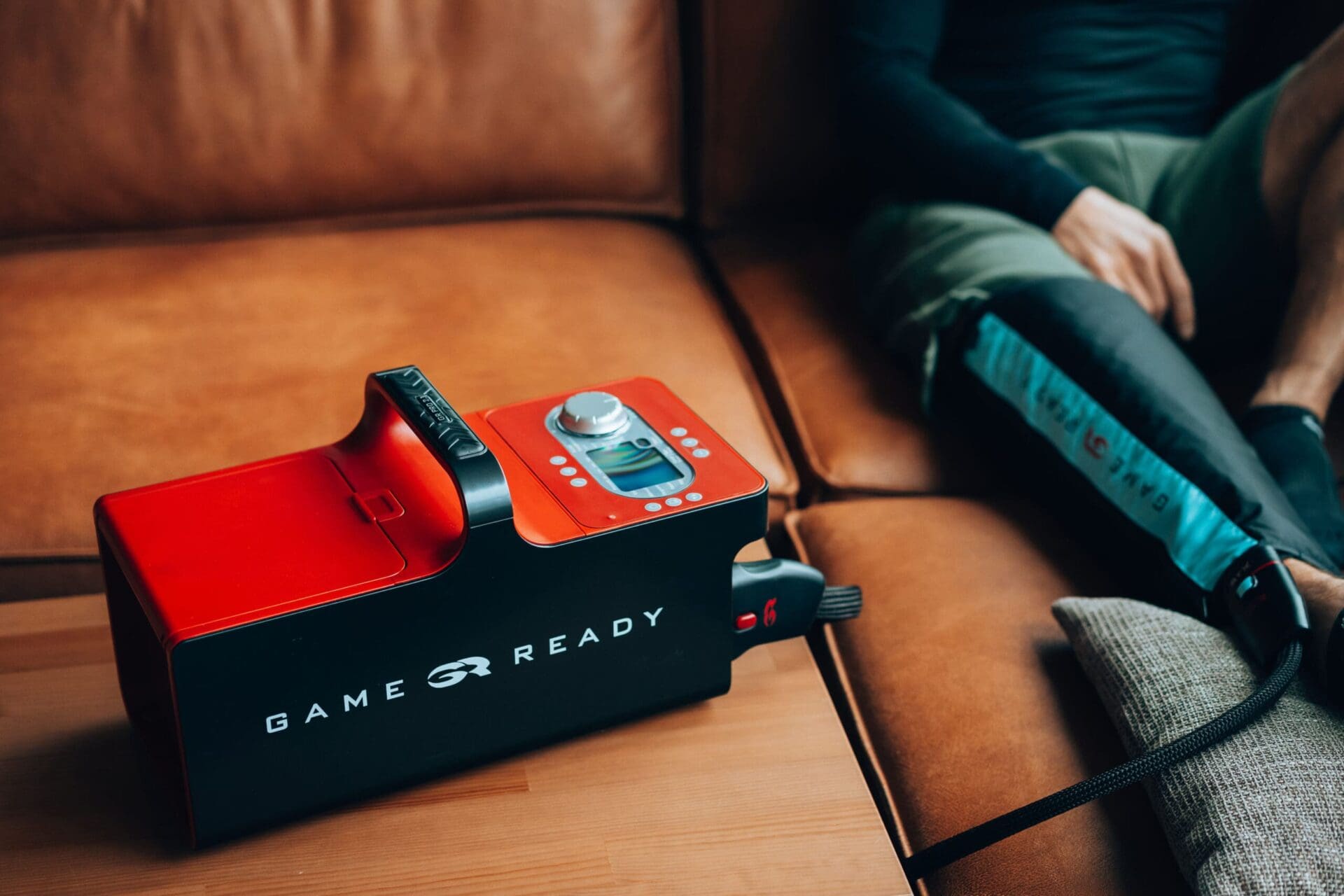 Stoswelle2 Ein Mann sitzt auf einer Couch und kühlt das rechte Bein mit dem Game-Ready System.